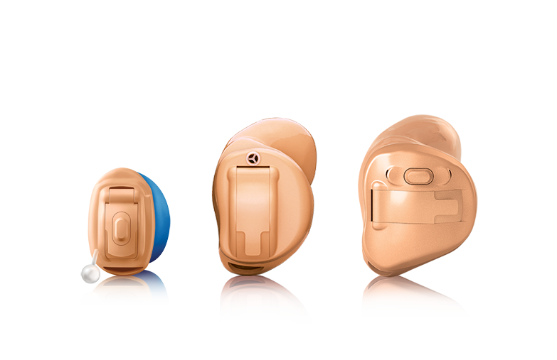 Three hearing aids are sitting next to each other on a white surface.