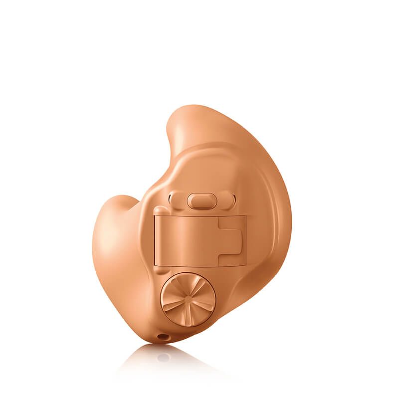A hearing aid is sitting on a white surface.