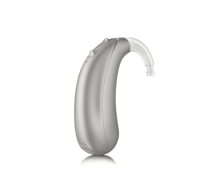 A silver hearing aid is sitting on a white surface