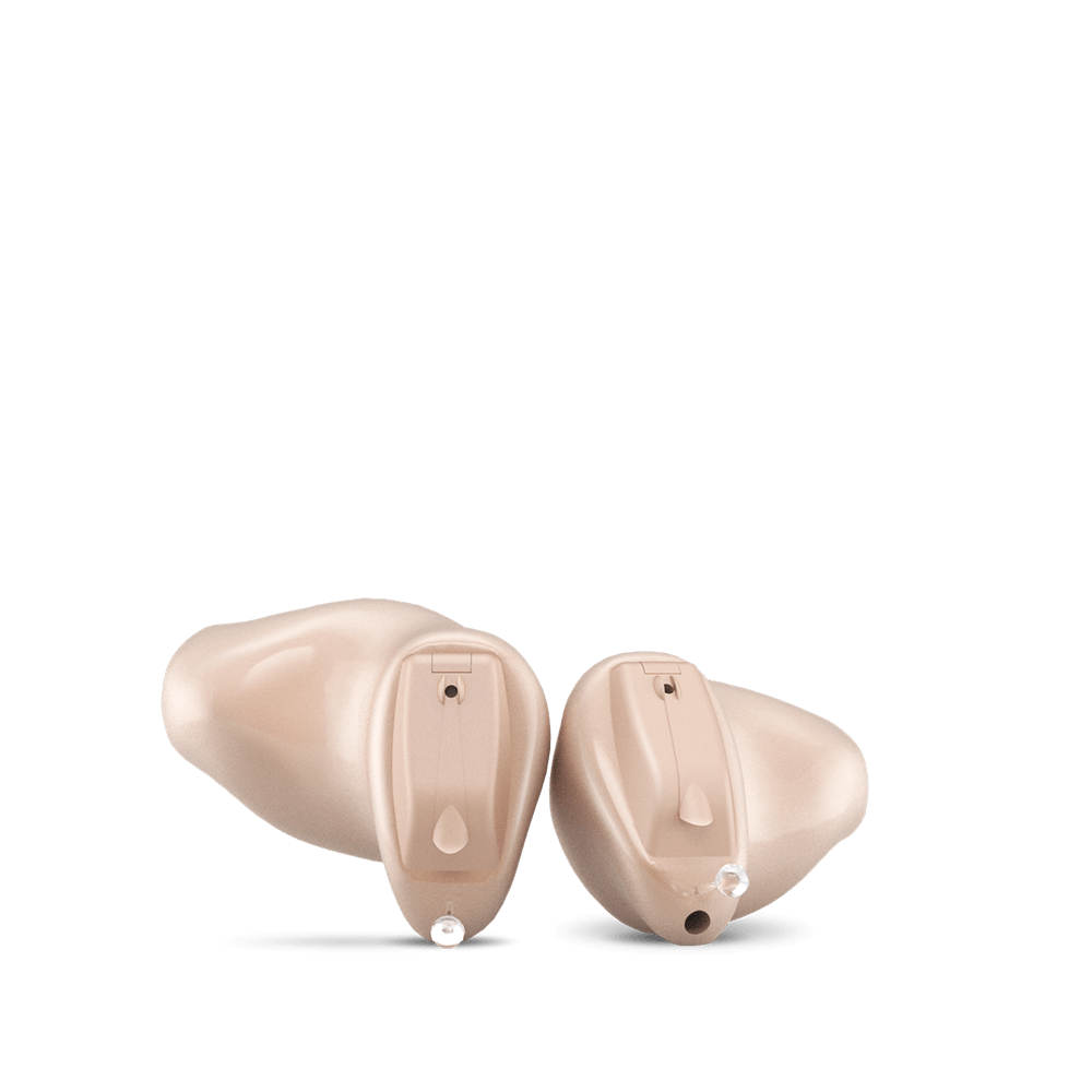 A pair of hearing aids are sitting next to each other on a white background.