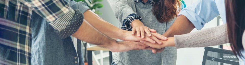 a group of people are putting their hands together in a huddle.