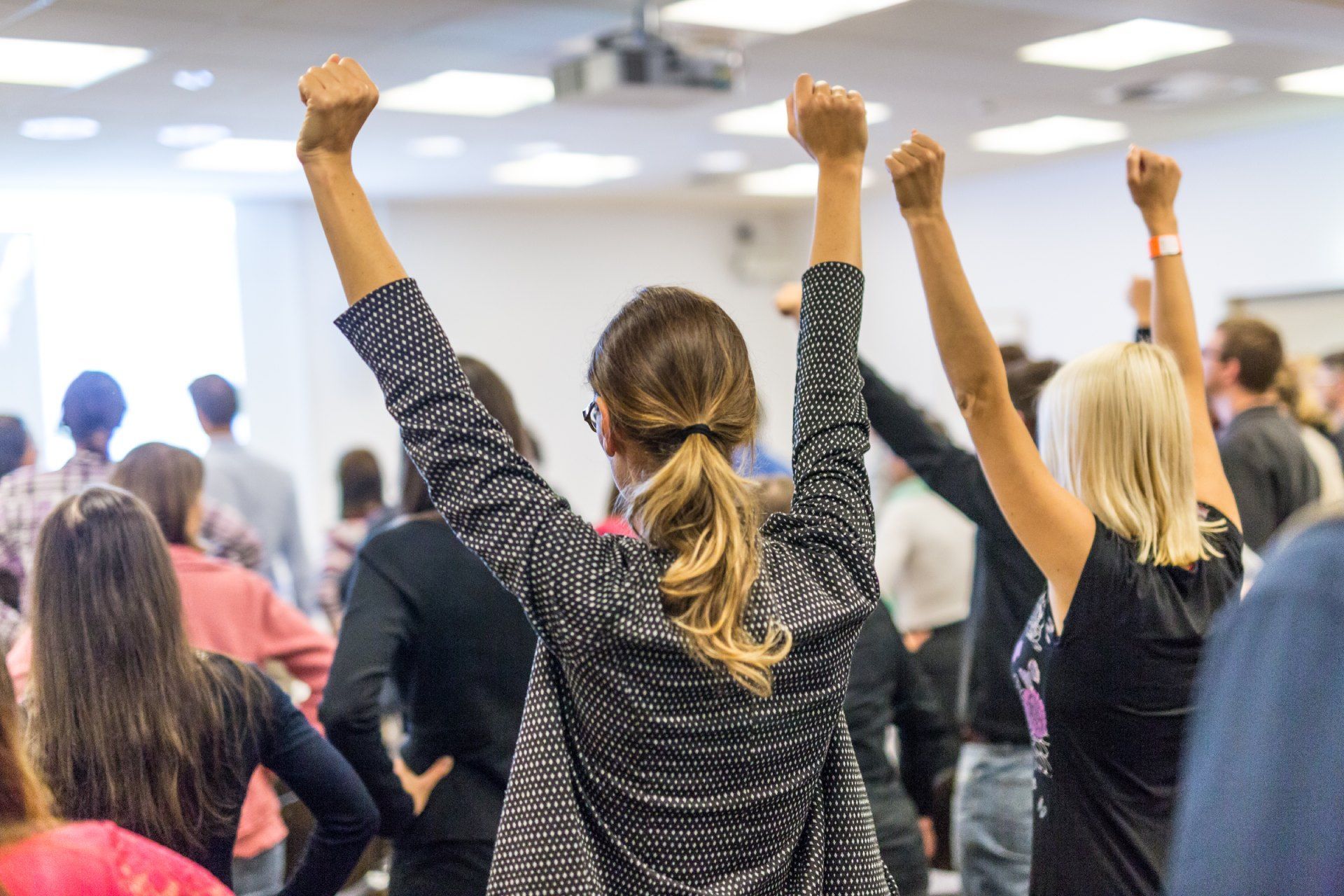 A group of people are standing in a room with their hands in the air.