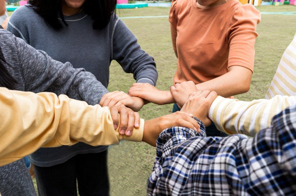 a group of people are putting their hands together in a circle.