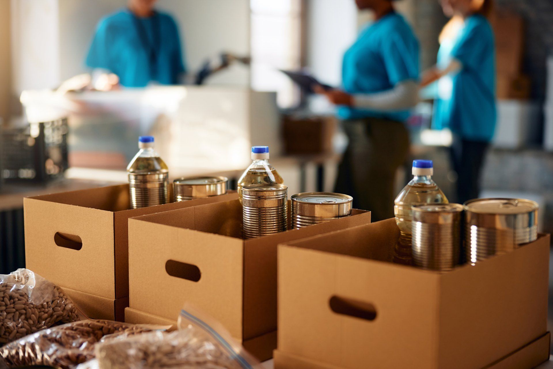 A row of cardboard boxes filled with food and bottles on a table.