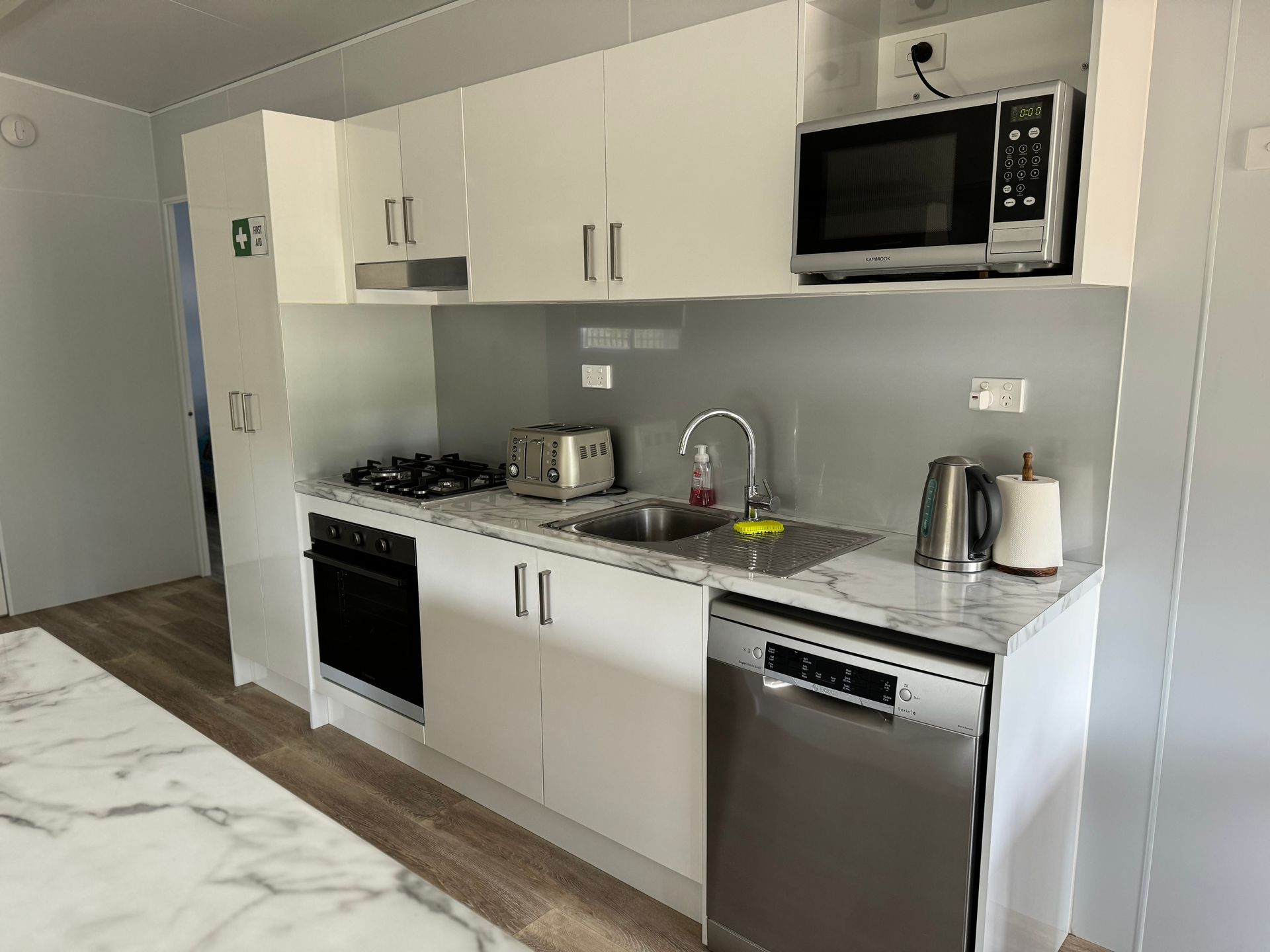 A kitchen with white cabinets , stainless steel appliances , a sink , and a microwave.