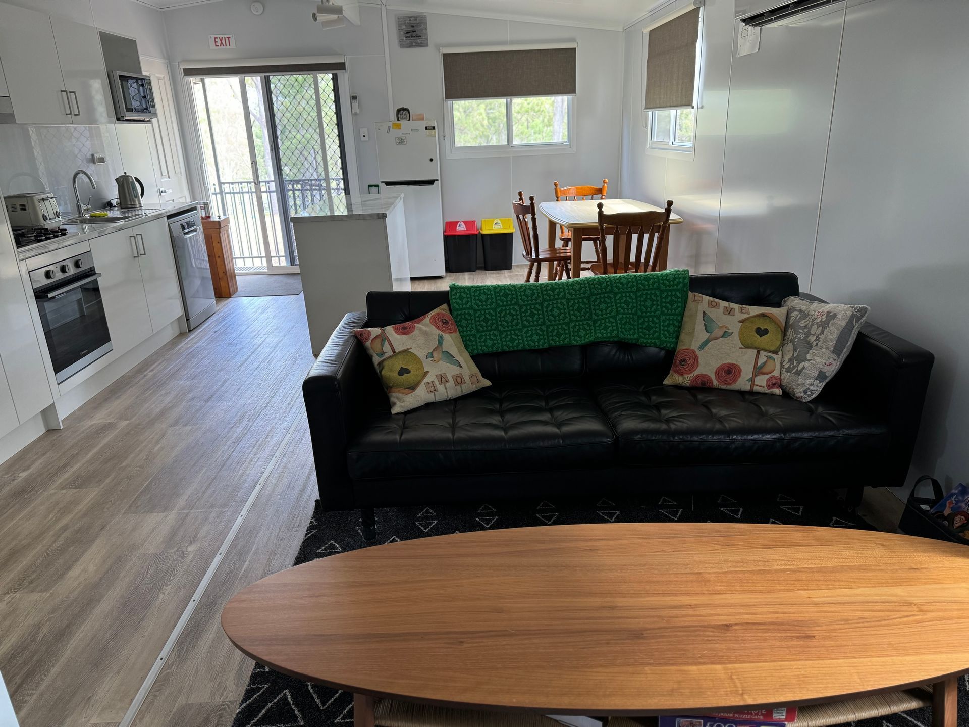 A living room with a black couch and a wooden coffee table.