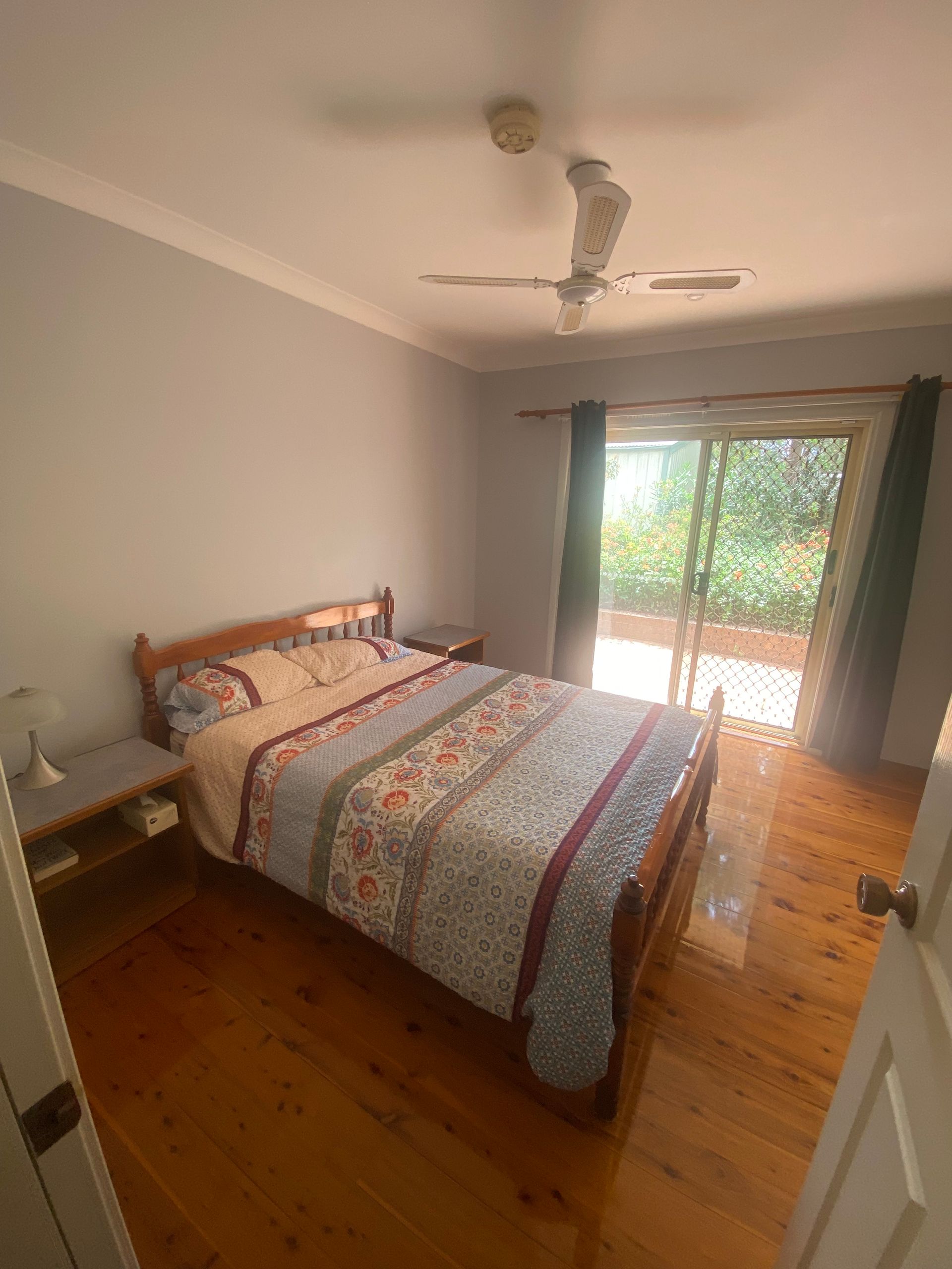 A bedroom with a king size bed and a ceiling fan.
