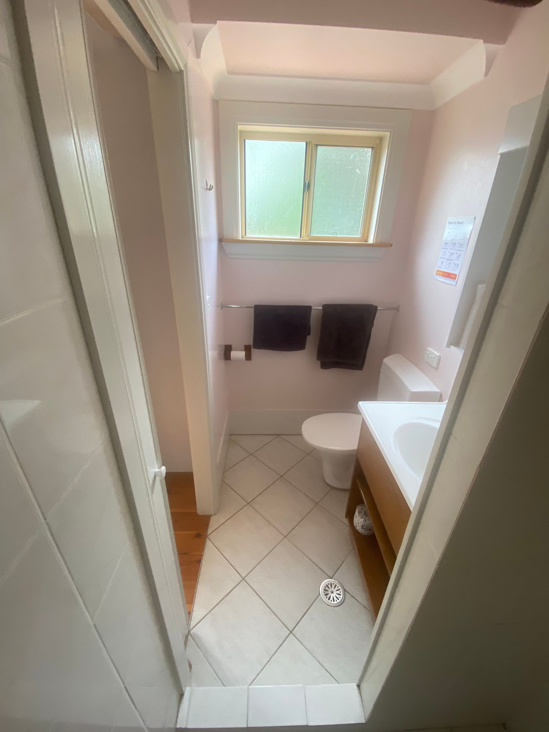 A bathroom with a toilet , sink , and window.