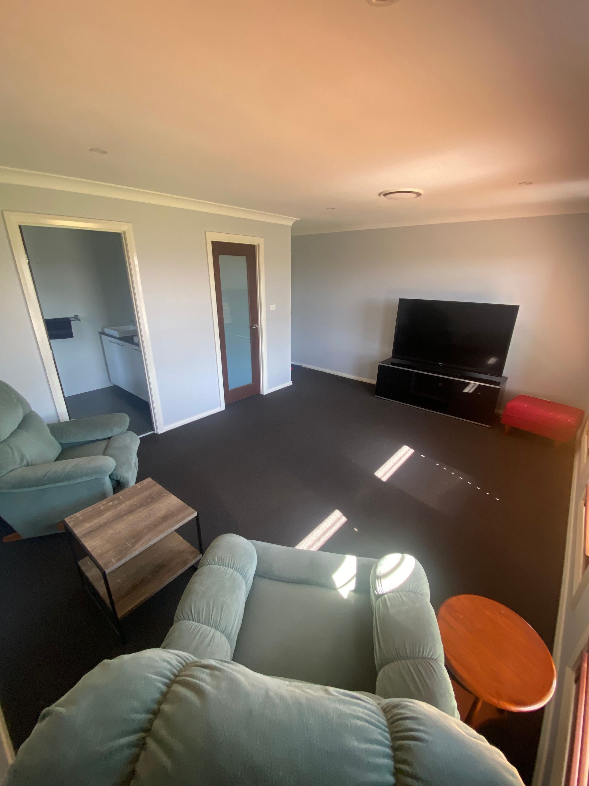 A living room with two chairs , a table and a television.