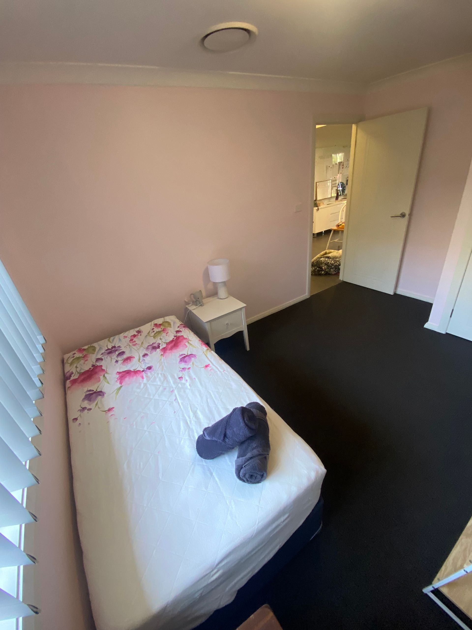 A bedroom with a single bed , nightstand , and lamp.