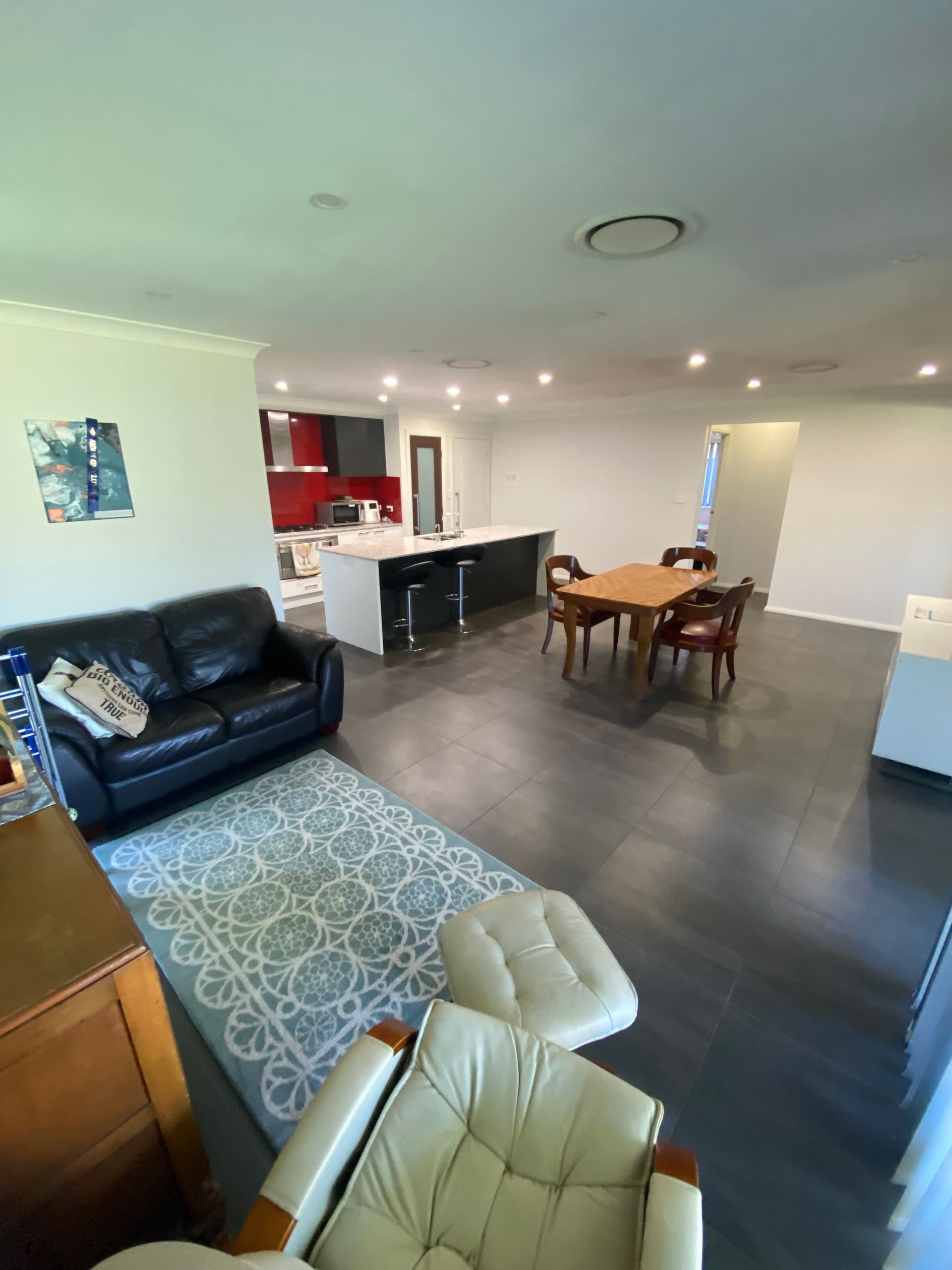 A living room with a couch , chairs , a table and a rug.
