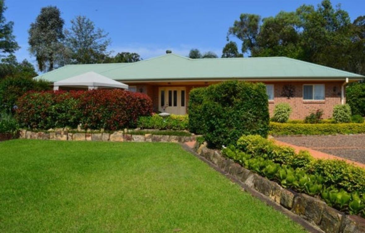 A large brick house with a green roof and a large lawn in front of it