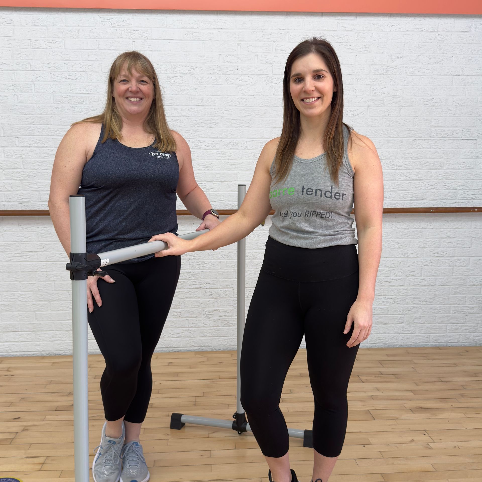Two women standing next to each other with one wearing a tank top that says ' pilates ' on it