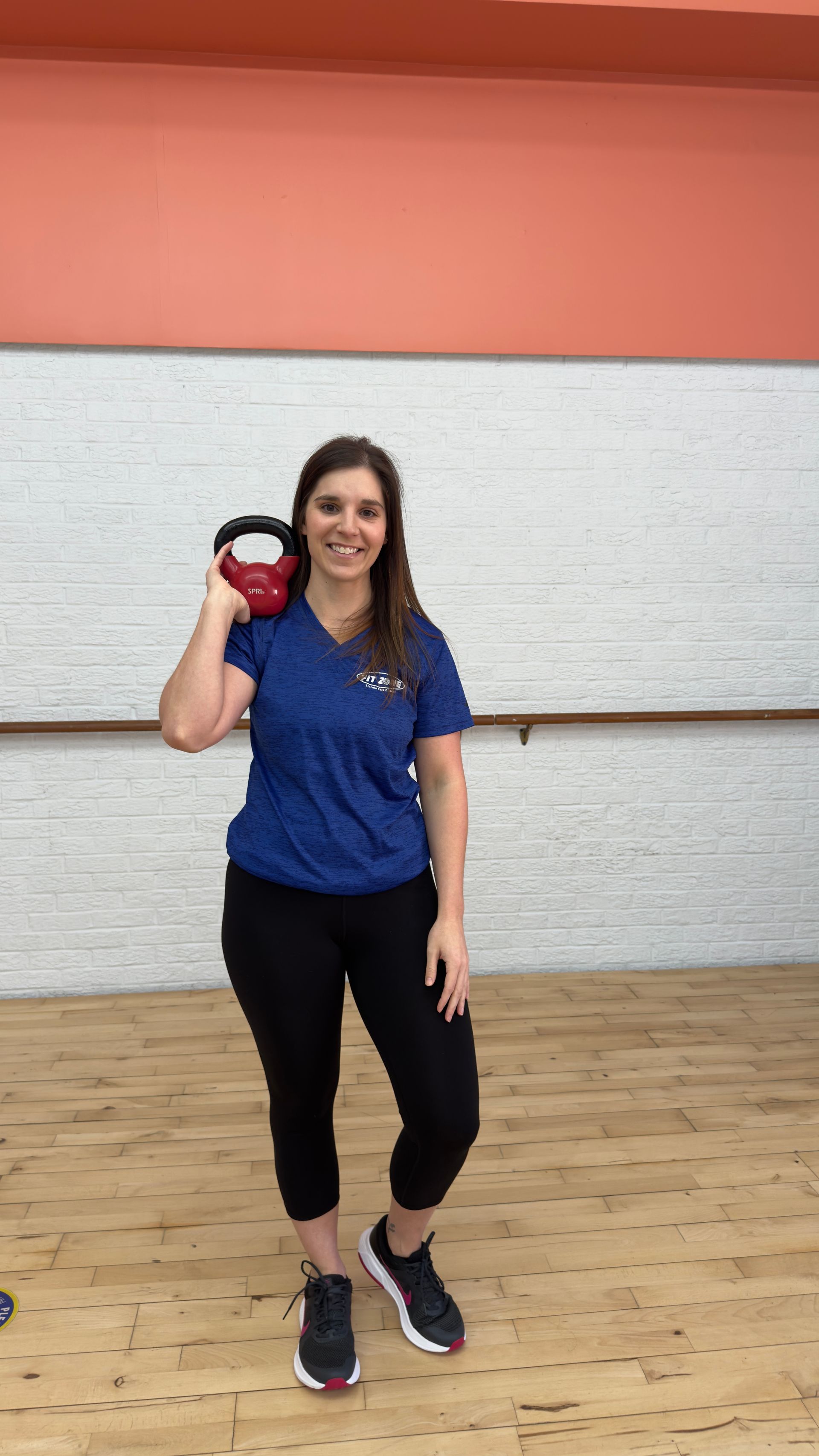 A woman is standing in a dance studio with her hands on her hips.