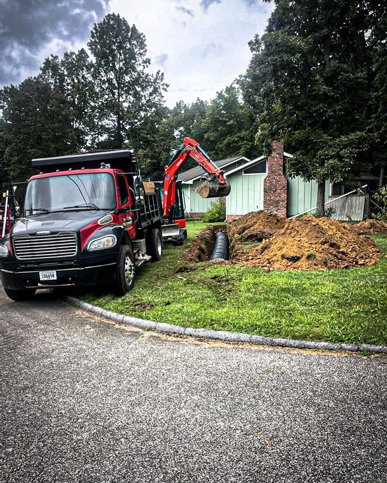 A dump truck and an excavator are parked in front of a house.