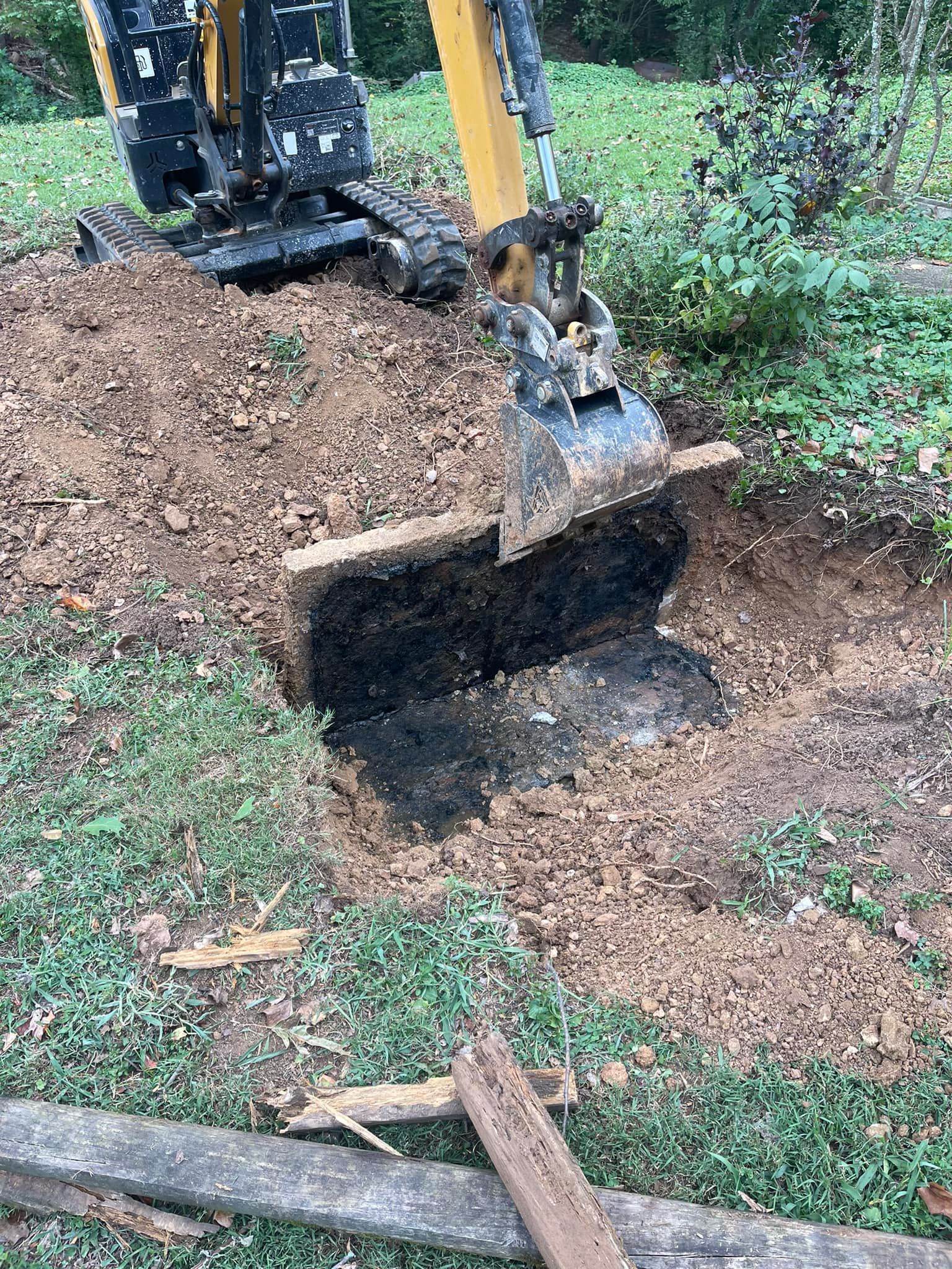 A man is sitting in the dirt next to a septic tank.