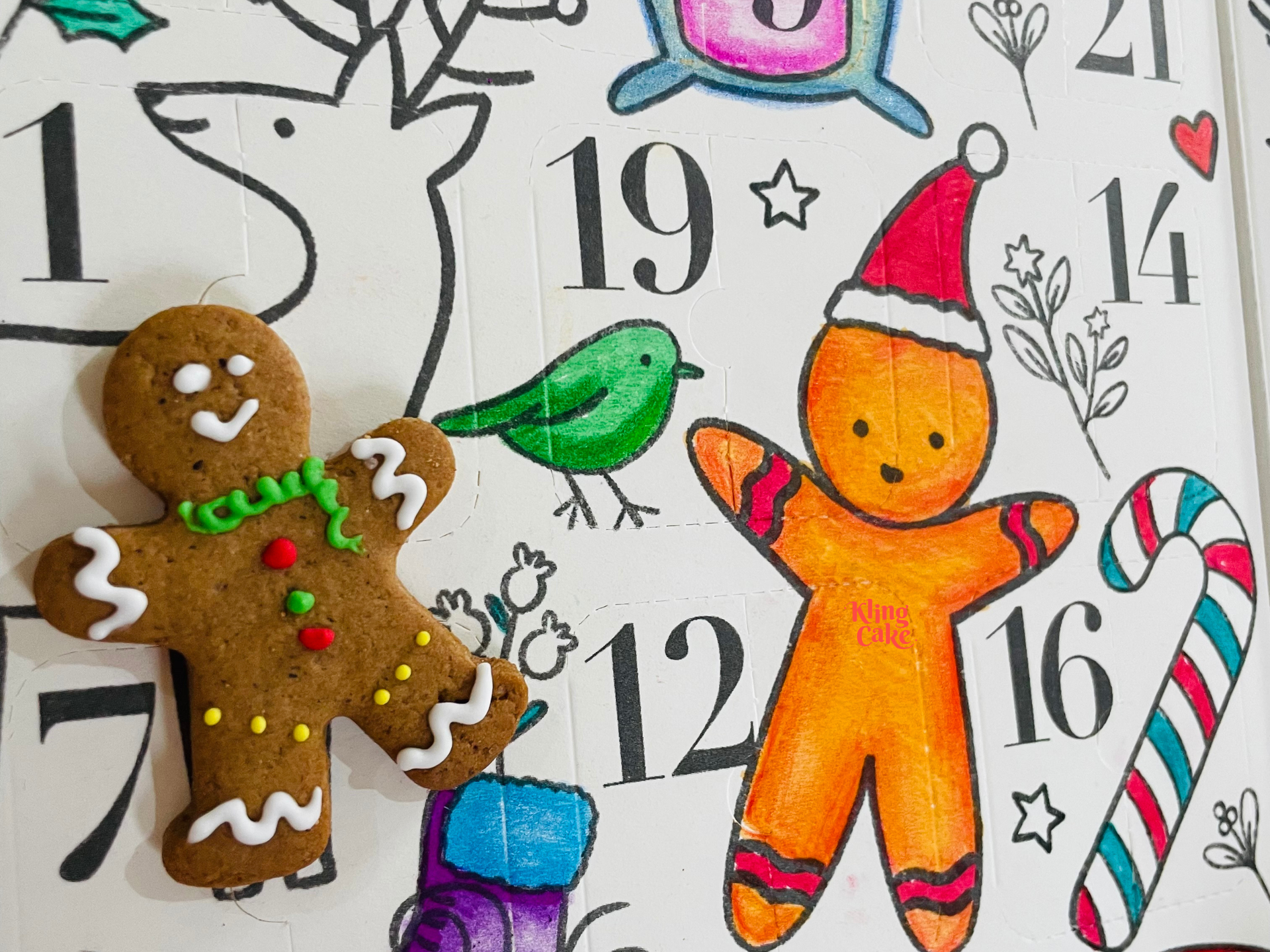 Hombre de jengibre decorado y figura de jengibre naranja con bastón de caramelo y pájaro verde sobre un fondo numerado de calendario de adviento