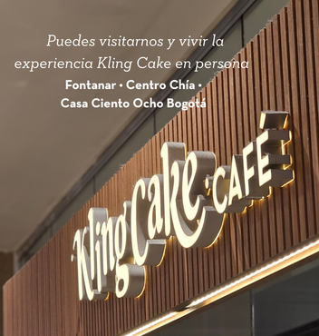 Letrero de Kling Cake Cafe en la fachada de madera de una tienda, con texto en español que invita a los visitantes a una experiencia con el