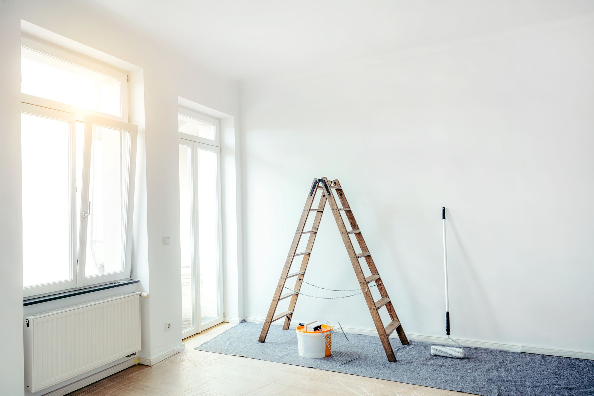 A man is painting the ceiling of a room with a roller.