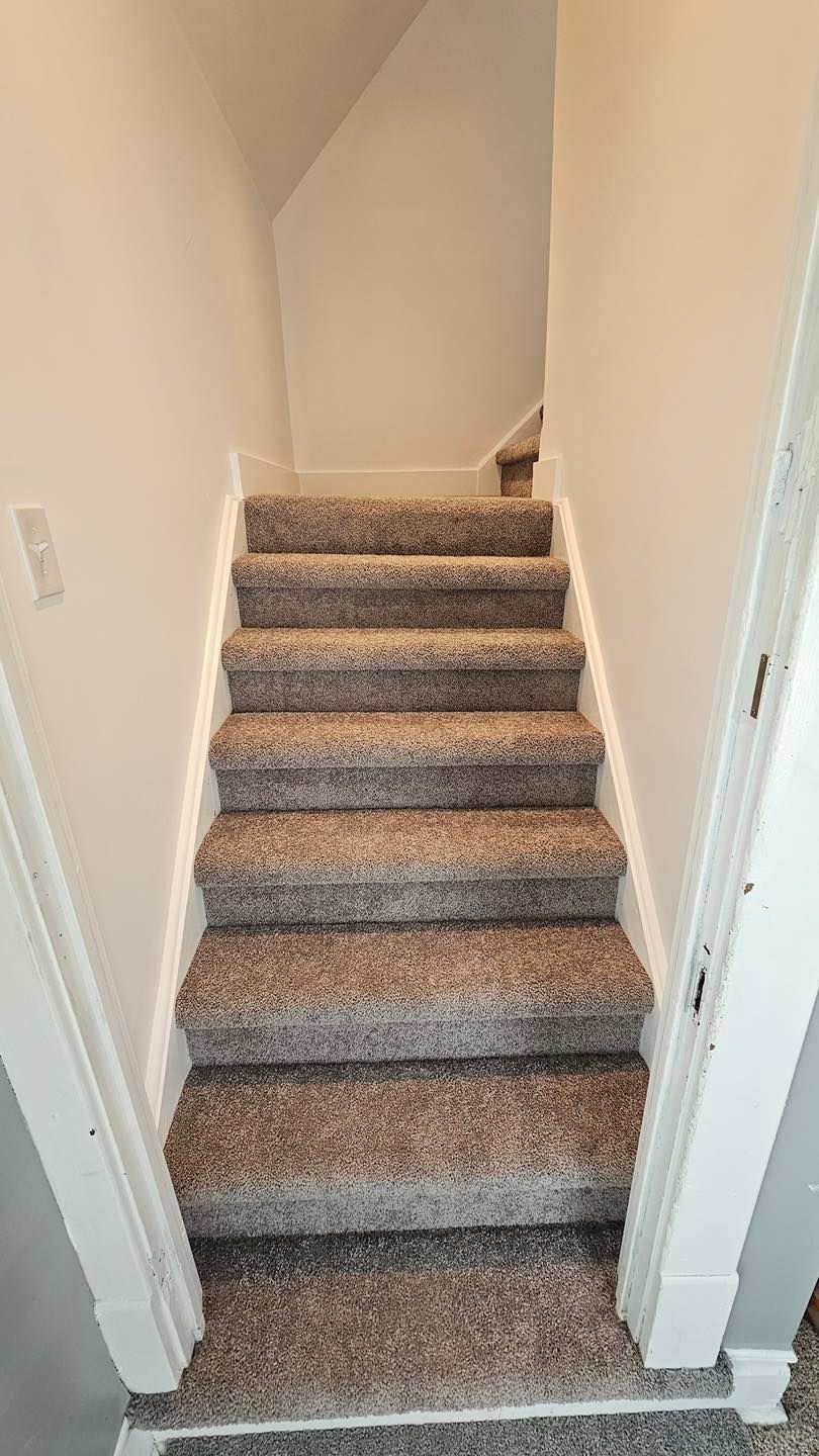 Staircase with brown carpet and white walls leading upwards.