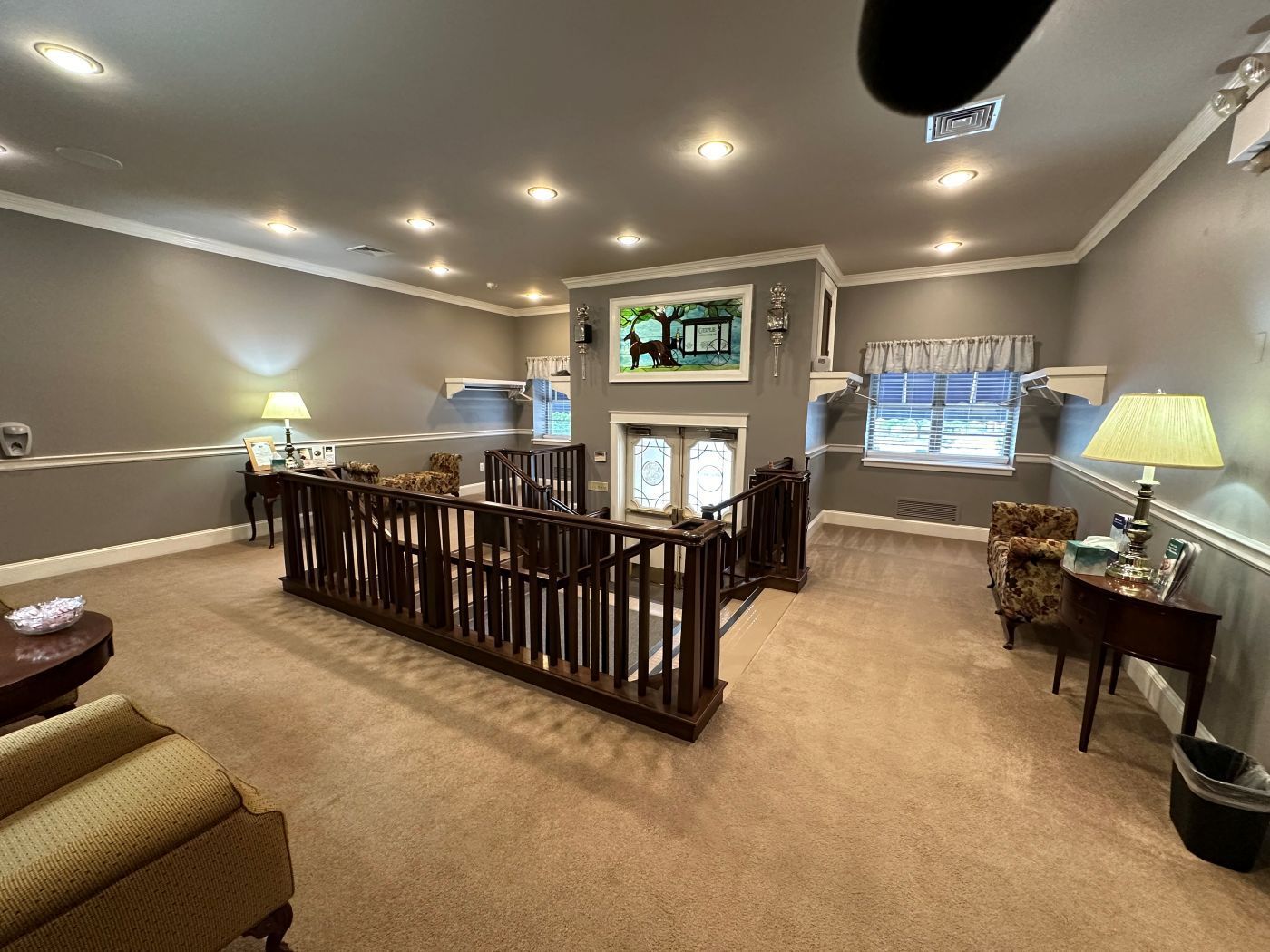 A living room with a balcony and a television on the wall.