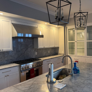 Modern kitchen with teal island, wood accent wall, open shelves, and bright white cabinets