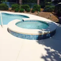 Poolside lounge with two chairs, umbrella, and a rectangular pool in a lush tropical garden