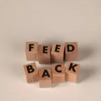 Wooden letter blocks spelling “FEED BACK” on a light background