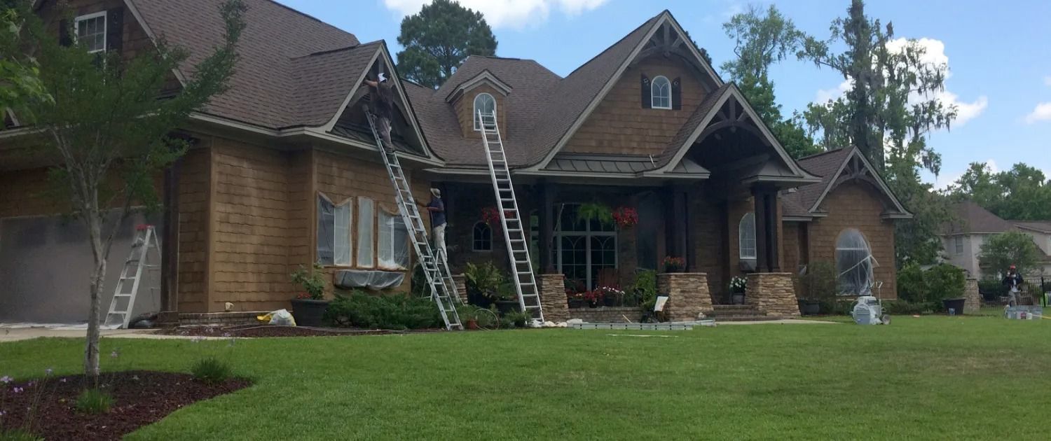 Suburban house with a ladder leaning against the roof and a lawn in front