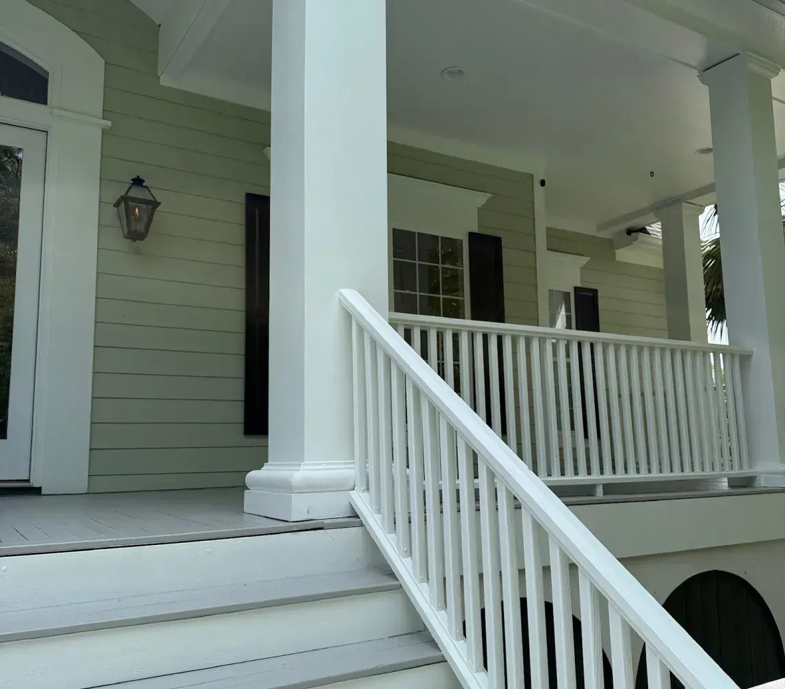 White house porch with stairs and railing leading to a covered front entrance
