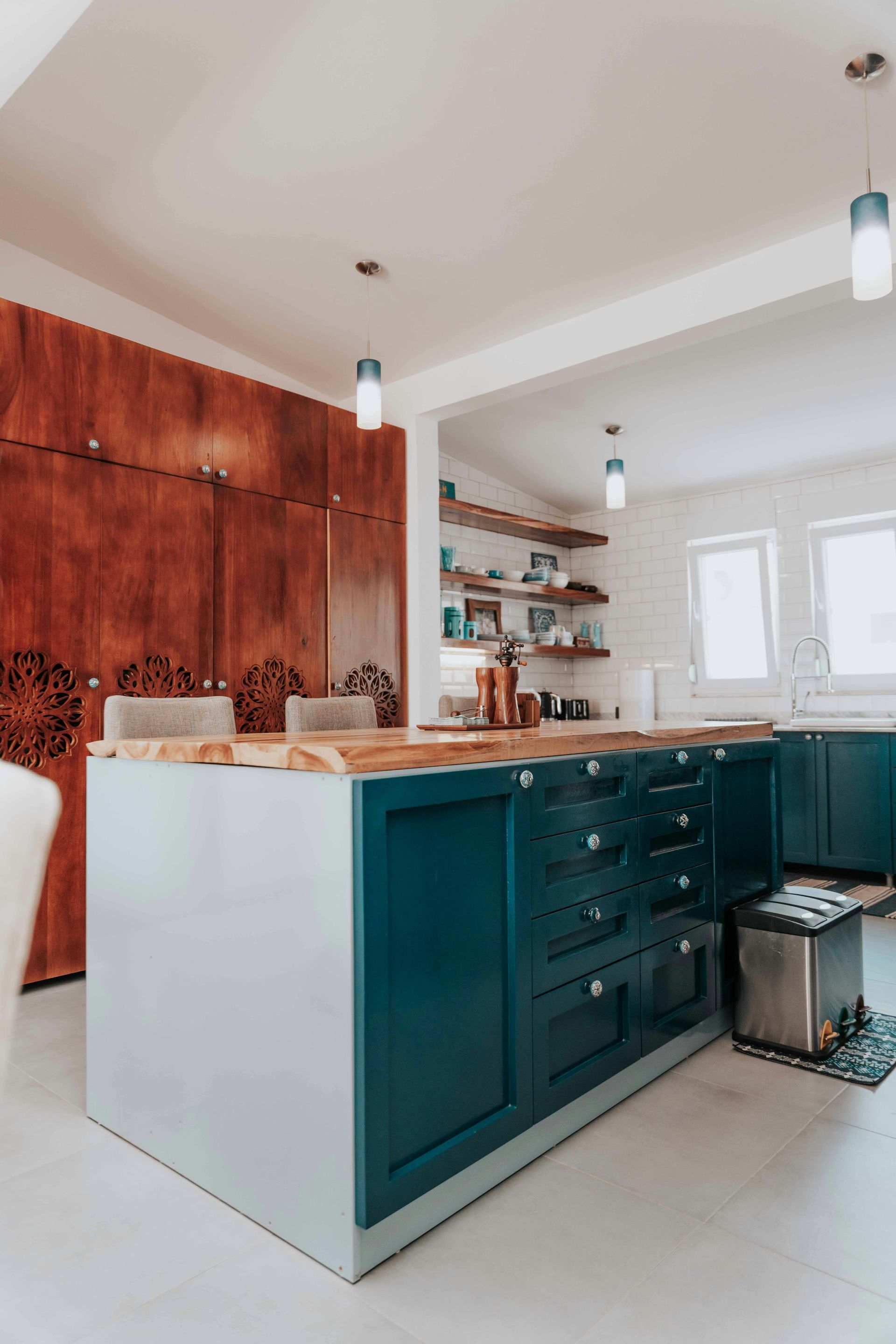 Modern kitchen with teal island, wood accent wall, open shelves, and bright white cabinets