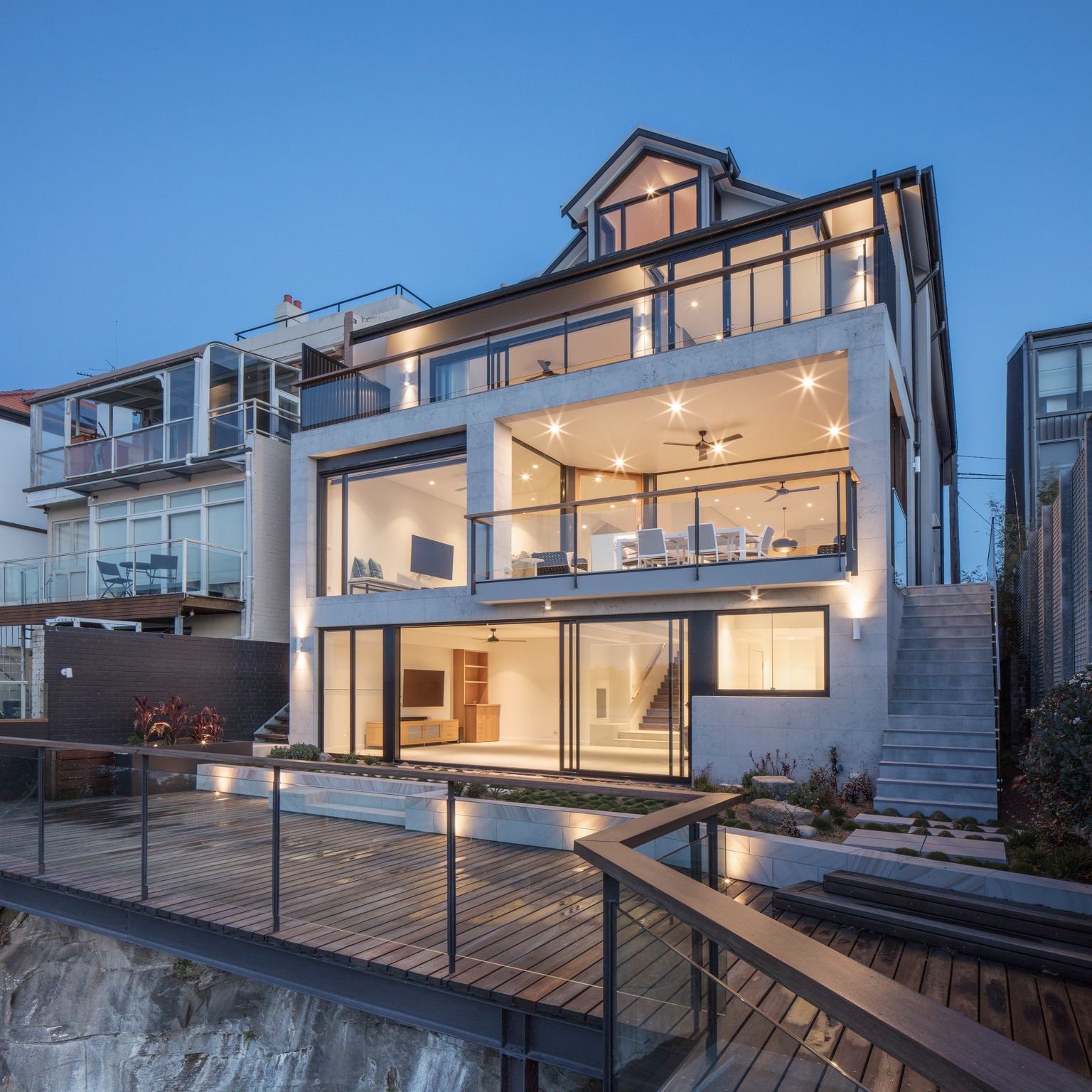 Modern Multi-story Home With Large Glass Windows and Outdoor Deck at Dusk — Burmah Constructions In Kangaroo Valley, NSW