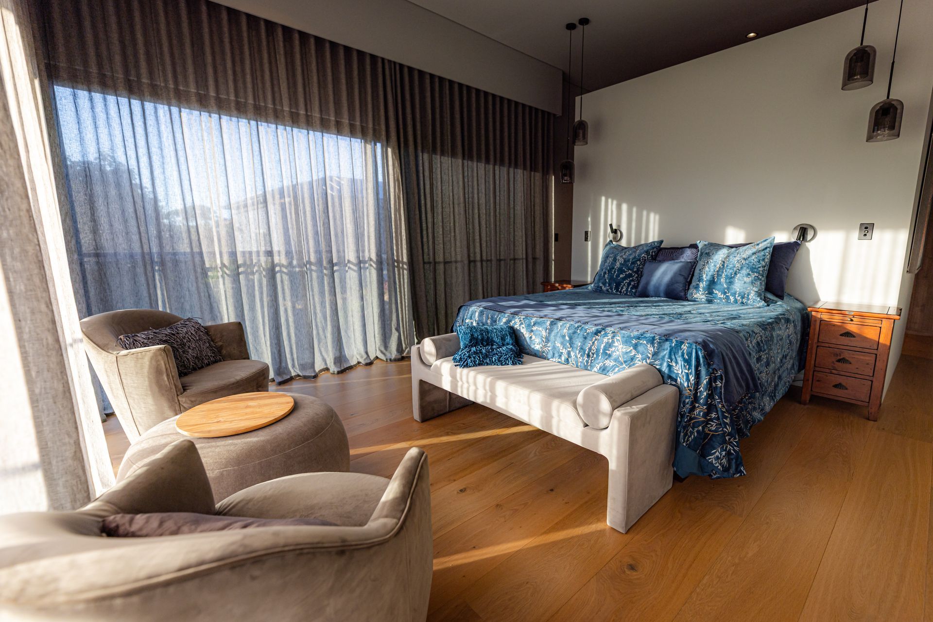 Bedroom With Large Bed, Floor-to-ceiling Curtains, and Warm Wood Flooring — Burmah Constructions In Kangaroo Valley, NSW