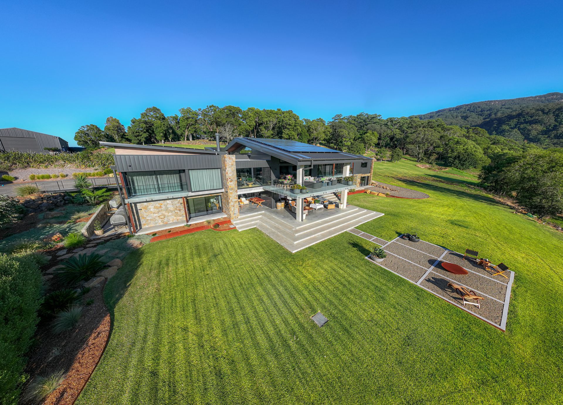 Modern House With Large Lawn, Patio, and Solar Panels on a Sunny Hillside — Burmah Constructions In Kangaroo Valley, NSW