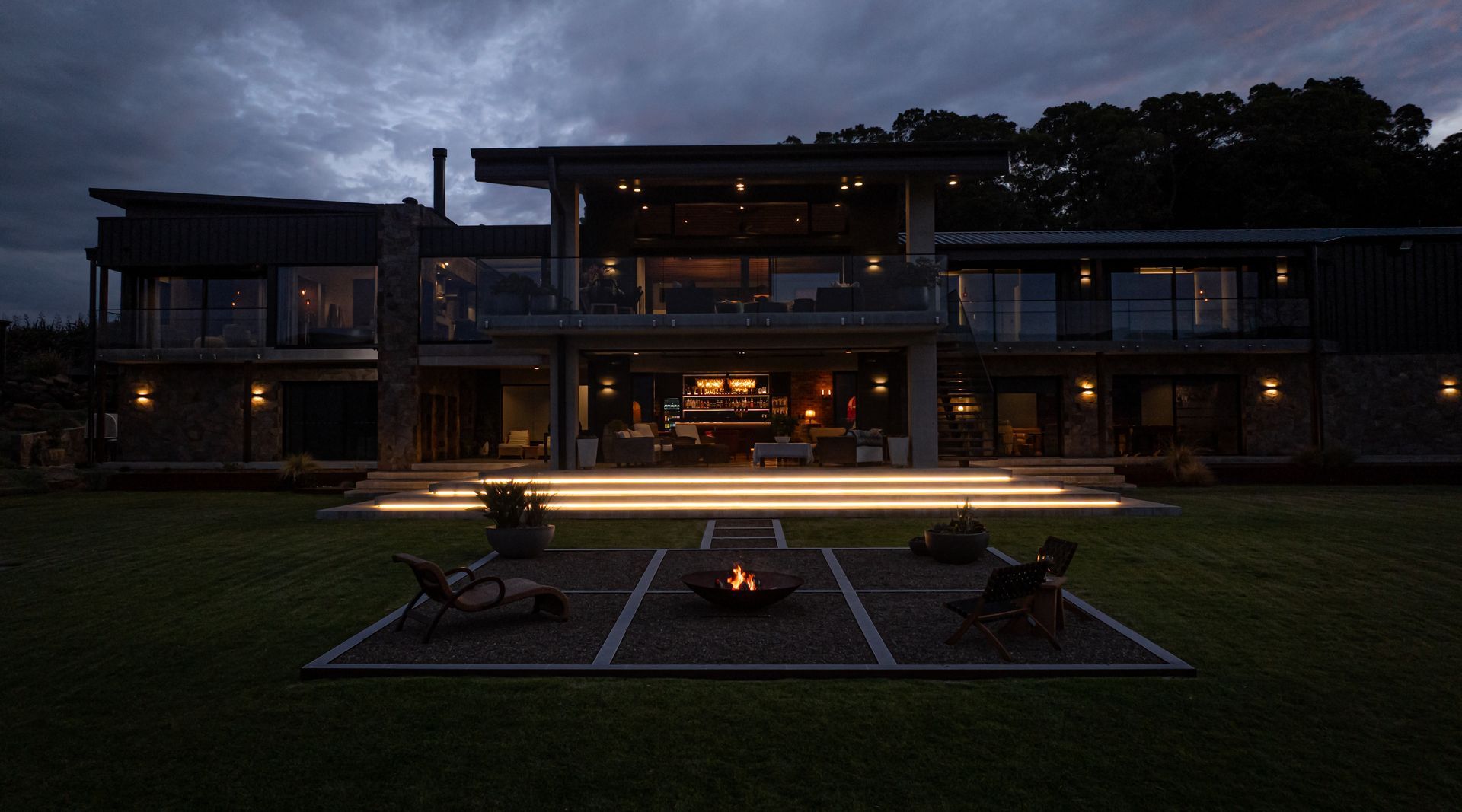 Modern House at Dusk With Warm Interior Lights and a Small Fire Pit — Burmah Constructions In Kangaroo Valley, NSW