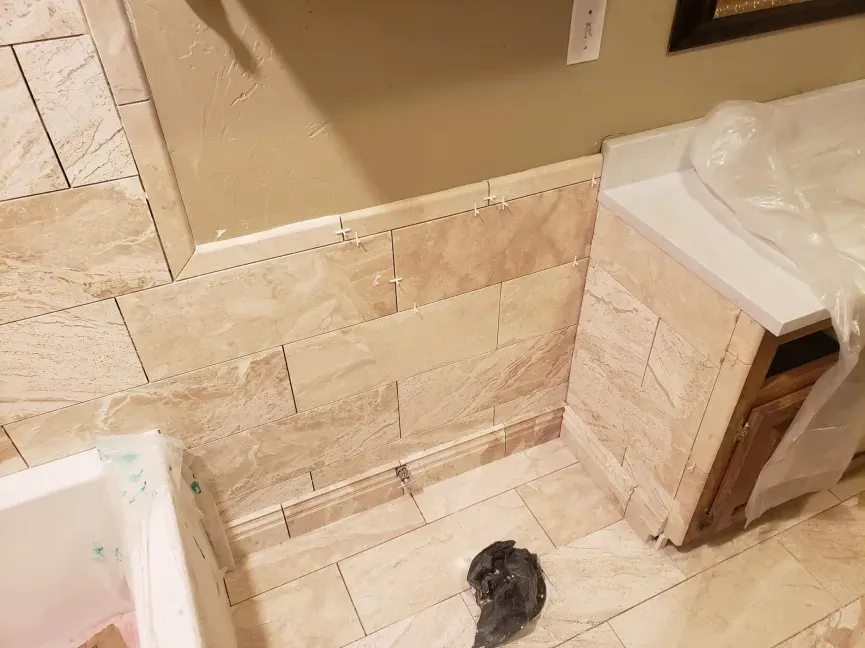 Tile bathroom corner with beige walls, a white toilet, and a dark object on the floor.