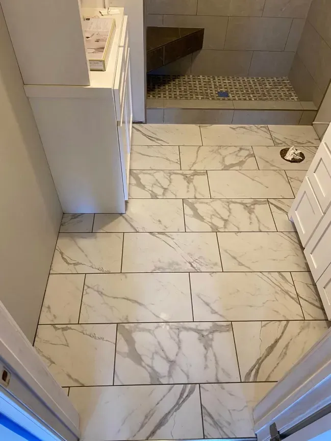Bathroom with white marble-look tile floor and shower area visible ahead