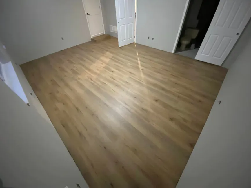 Empty room with light wood flooring, white walls, and open doors.