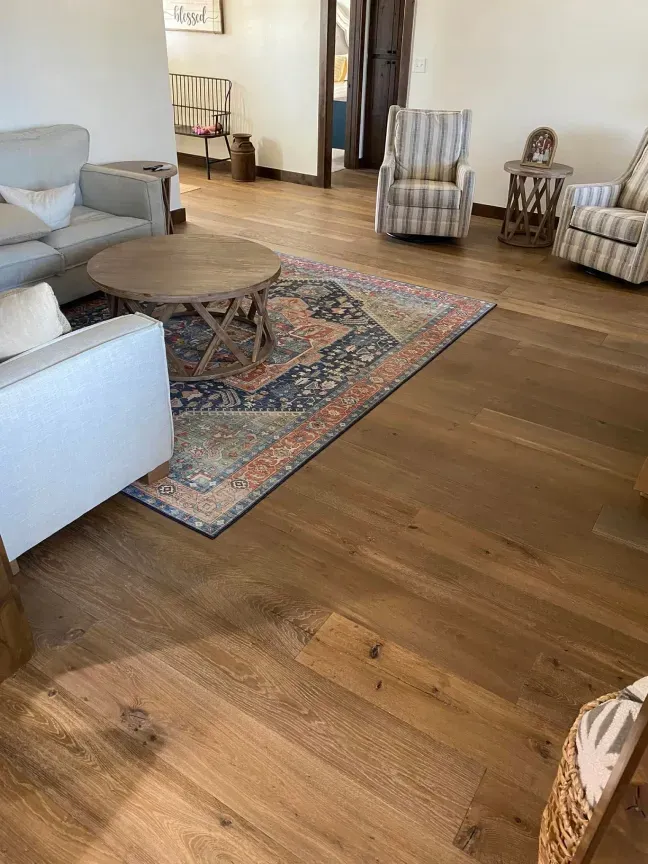 Living room with hardwood floors, sofa, patterned rug, round coffee table, and striped accent chairs