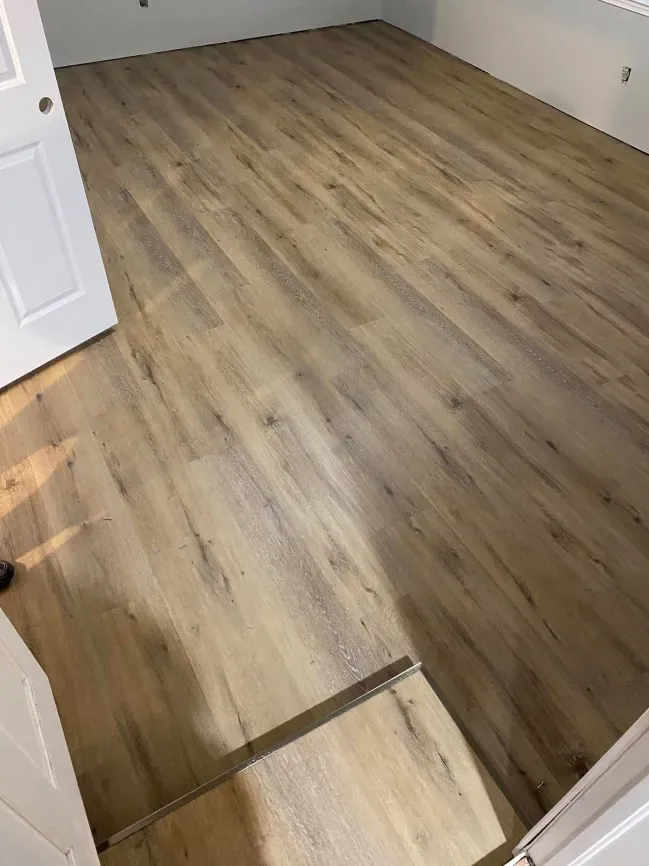 Empty room with light wood flooring and an open doorway in the foreground