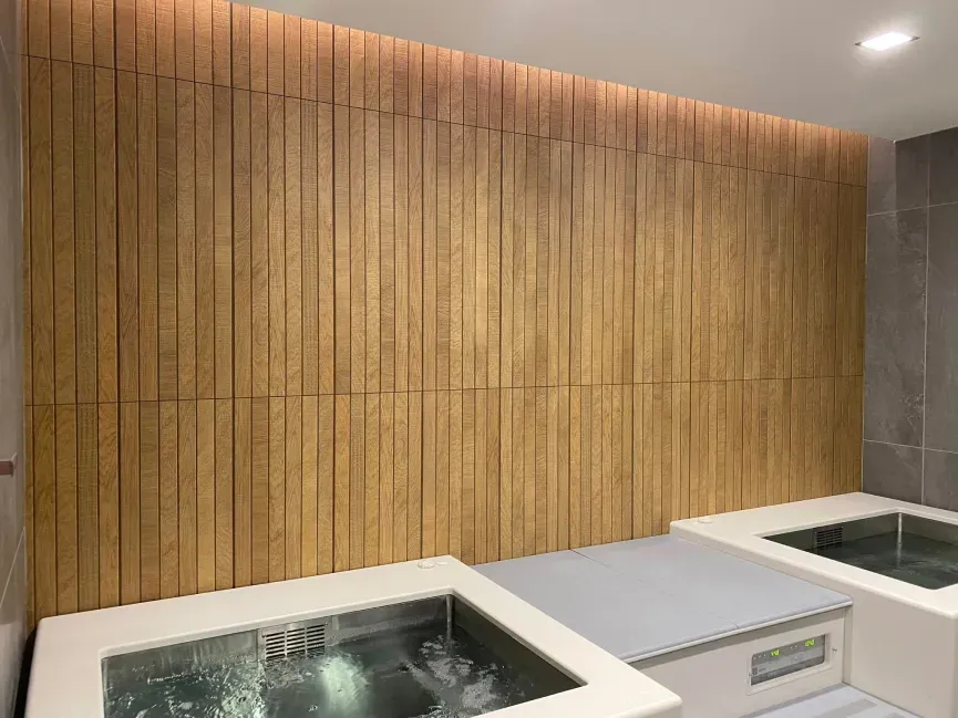 Modern spa room with a wooden accent wall and two white rectangular soaking tubs.