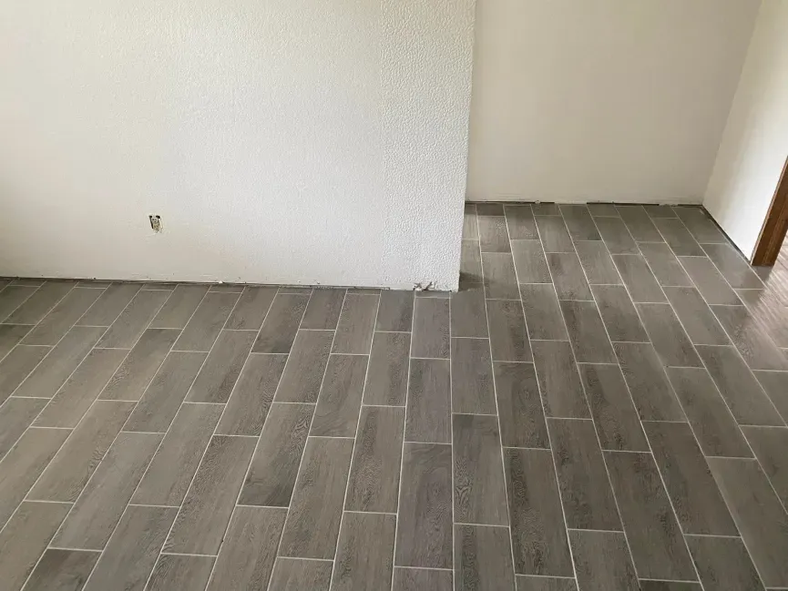 Empty room corner with gray tile floor and white textured walls