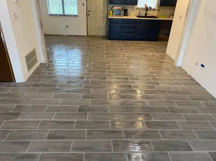 Empty room with glossy gray tile floor, white walls, and a blue cabinet against the far wall.