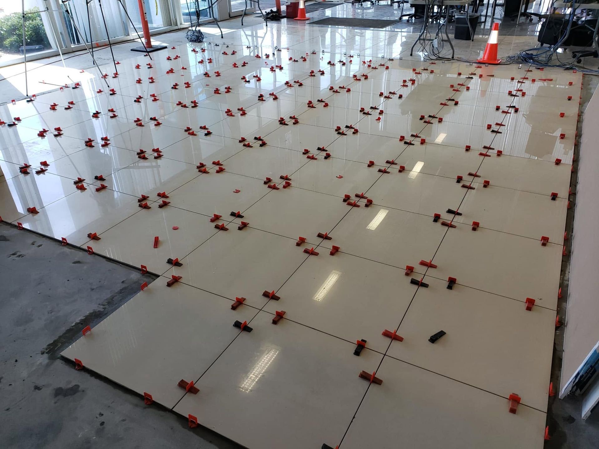 Indoor tiled floor with many red tile-level markers or spacers arranged in a grid pattern