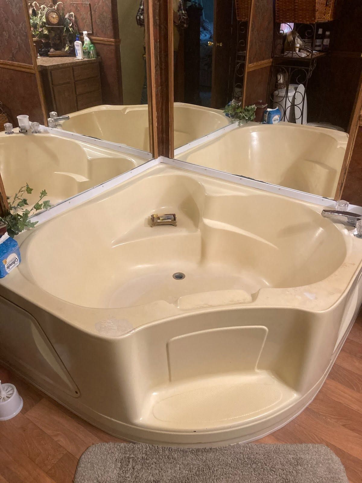 Beige corner jetted bathtub with mirrored walls and wood-paneled bathroom setting