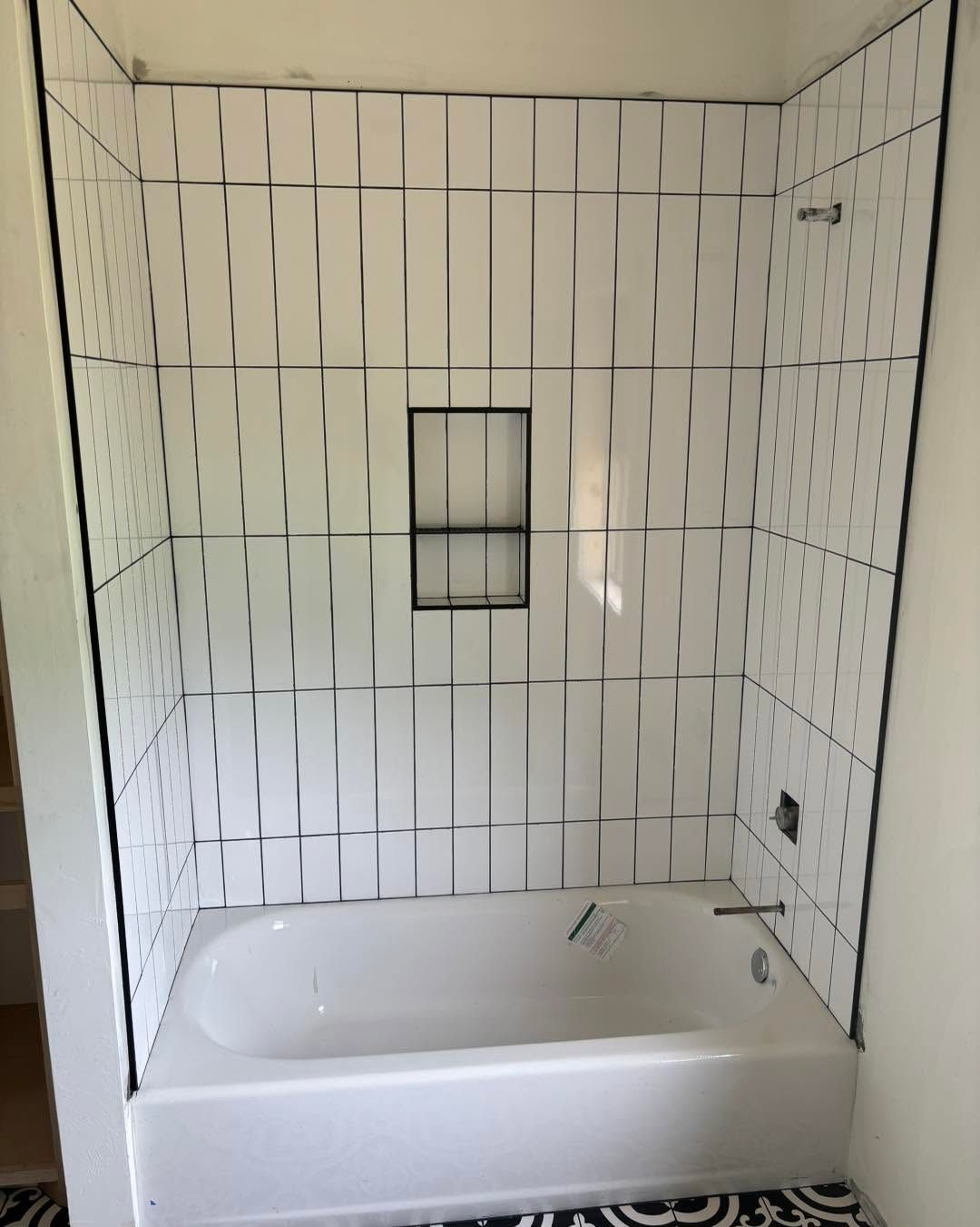 Bathroom with white tiled shower-tub combo and a small built-in niche.