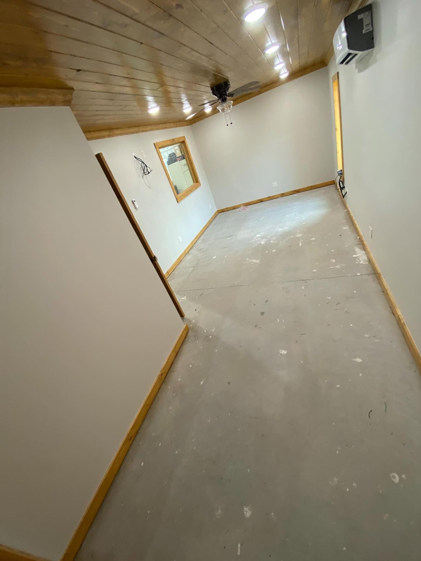 Empty hallway with white walls, wood trim, and a wooden ceiling, viewed at a tilted angle.