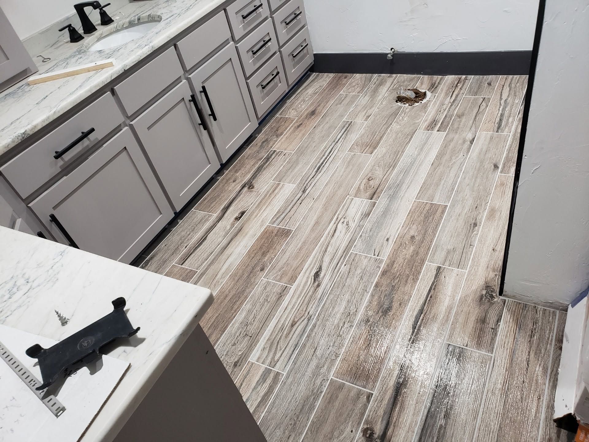 Empty kitchen with gray cabinets, wood-look floor, and a countertop corner in the foreground