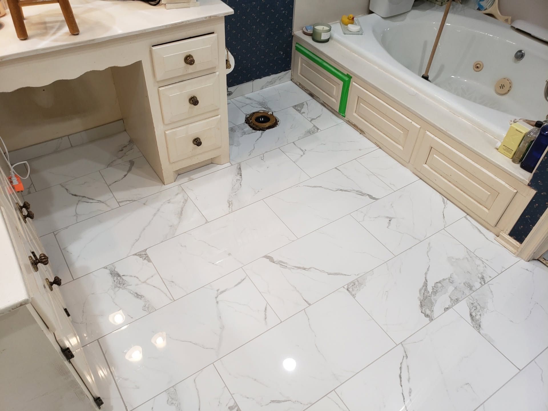 Bathroom with white marble-look tile floor, vanity, and built-in bathtub under renovation.