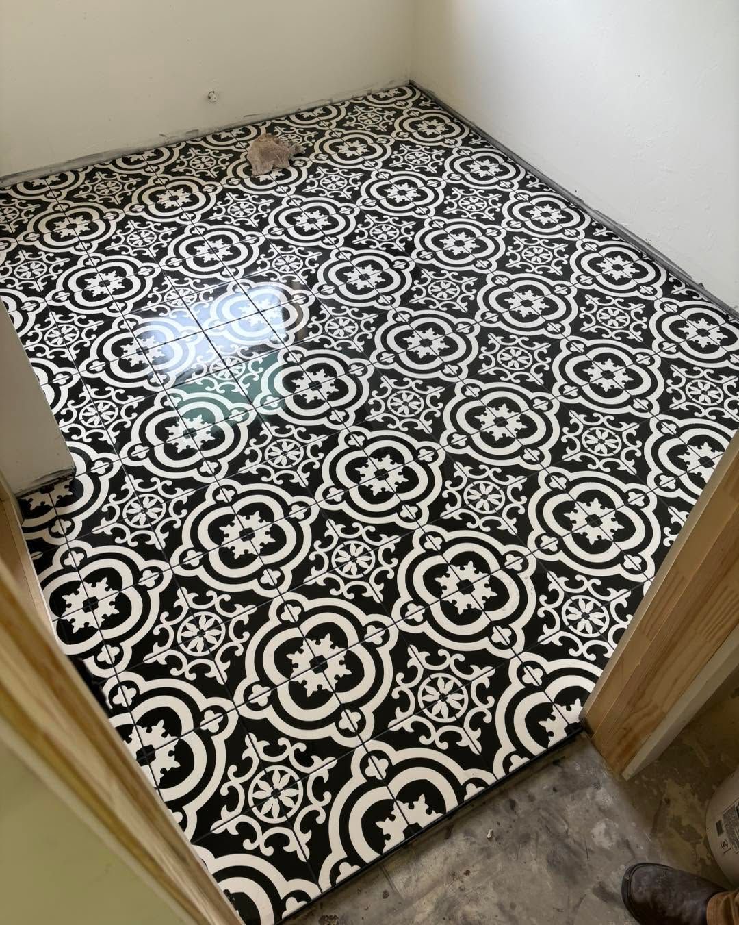 Small room with black-and-white patterned flooring and a wet patch near the doorway.